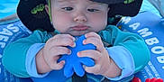 Cooper is registered to the contest to win money with this photo: baby, hat, blue, floatation_device, toy, blue_octopus, red_crab_toy, water, swimming, child, infant, sun_hat, outdoor, summer, safety_strap, closeup, cute, playful, seat, concentration