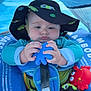 baby, hat, blue, floatation_device, toy, blue_octopus, red_crab_toy, water, swimming, child, infant, sun_hat, outdoor, summer, safety_strap, closeup, cute, playful, seat, concentration
