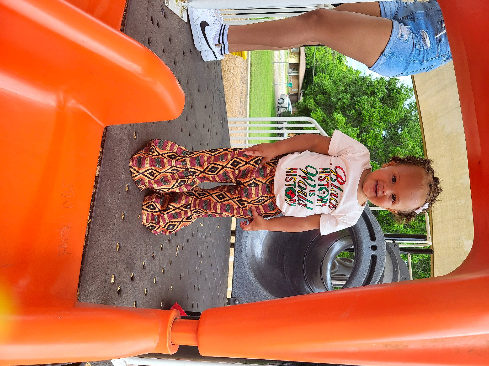 Jaliyah is registered to the contest to win money with this photo: automotive_design, automotive_exterior, blue, child, chute, fun, grass, hood, joy, leisure, motor_vehicle, orange, outdoor_play_equipment, person, play, playground, recreation, red, t_shirt, toddler