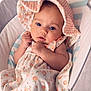 baby, infant, blue_eyes, hat, dress, peach_pattern, bassinet, blanket, cute, child, sleeping_area, soft, clothing, portrait, newborn, resting, indoors, comfort, toddler, adorable