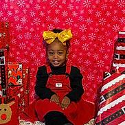 Leilani joined the competition — help win amazing prizes! black_shirt, carpet, celebration, child, christmas, cute, festive, gift_wrap, girl, golden_bow, happy, holiday, indoor, portrait, presents, red_dress, reindeer_pillow, sitting, smiling, snowflake_pattern