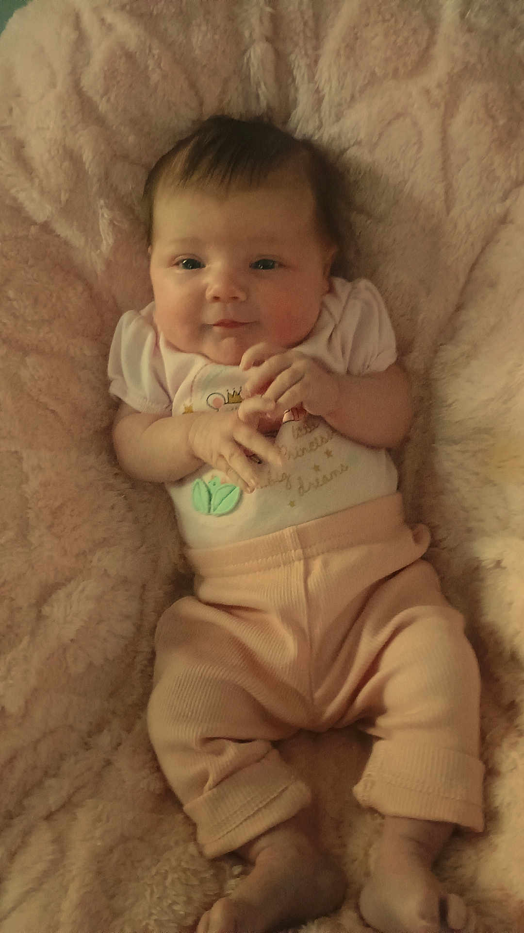 Presley is registered to the contest to win money with this photo: baby, infant, blanket, pink, clothing, cute, hands, face, lying_down, soft_texture, toddler, portrait, smile, warm, cozy, child, person, indoors, relaxing, young