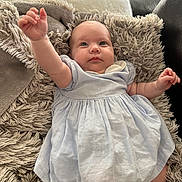 June participe au concours pour gagner de l'argent avec cette photo : baby, blue_dress, child, couch, cozy, cute, dress, fluffy_rug, hand, head, indoor, infant, lying_down, person, portrait, raising_arm, skin, smiling, soft_texture, young_child