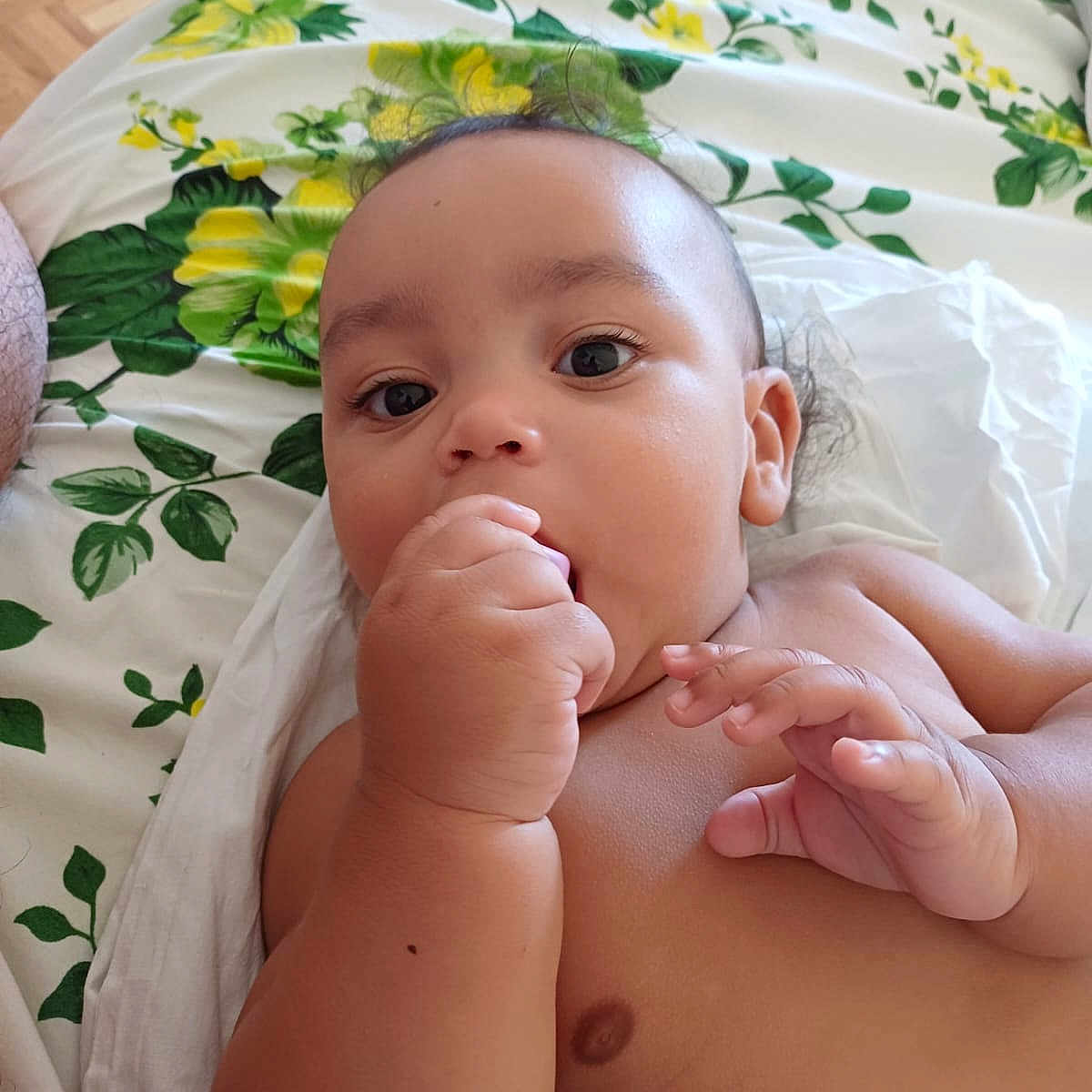 Adonaï participe au concours pour gagner de l'argent avec cette photo : baby, bed, blanket, child, closeup, curious, cute, expression, face, fingers, floral_pattern, hand, indoors, infant, lying_down, person, resting, skin, sleepwear, young