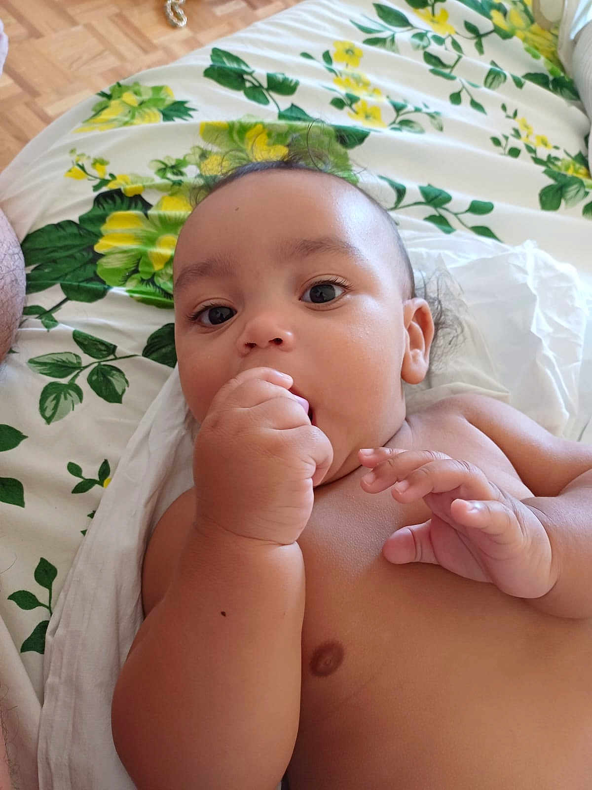 Adonaï participe au concours pour gagner de l'argent avec cette photo : baby, infant, hand, face, skin, bed, blanket, floral_pattern, lying_down, curious, cute, indoors, child, young, person, closeup, expression, fingers, sleepwear, resting