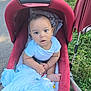 baby, stroller, blanket, outdoor, grass, sidewalk, child, infant, cute, curious, person, seated, clothing, foot, hand, red, blue, nature, daylight, portrait
