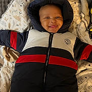 Nyliane participe au concours pour gagner de l'argent avec cette photo : apparel, baby, blanket, child, cozy, cushion, cute, fabric, face, happy, hooded_jacket, indoor, infant, lying_down, person, portrait, smiling, soft, warm, winter_clothing