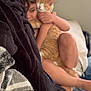 child, cat, hugging, blanket, indoor, bed, comfort, pet, ginger_cat, cuddling, smiling, relaxed, legs, skin, furniture, home, cozy, soft_lighting, close_up, happy