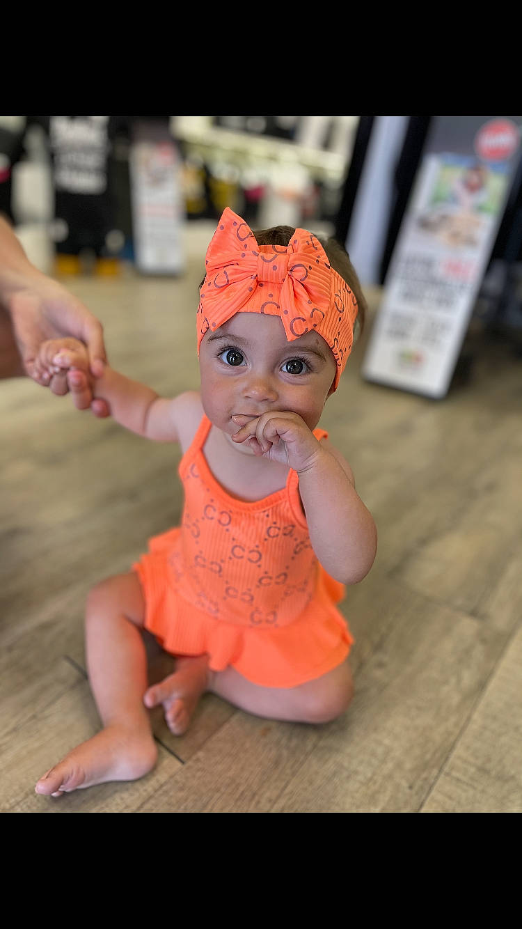 Joy a rejoint le concours — aidez-le/la à gagner de superbes lots ! baby, baby_toddler_clothing, cheek, child, eye, fashion_accessory, fawn, finger, foot, fun, happy, headwear, human_body, human_leg, orange, peach, person, sitting, skin, street_fashion