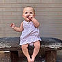 baby, child, infant, sitting, bench, stone_bench, brick_wall, dress, light_purple, smiling, happy, cute, finger_in_mouth, barefoot, outdoor, portrait, person, young_child, innocence, joy