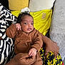 Nayra a rejoint le concours — aidez-le/la à gagner de superbes lots ! baby, infant, person, hand, clothing, couch, pillow, blanket, patterned_clothing, indoor, skin, face, hair, holding, seated, textile, colorful, comfort, relaxation, cute