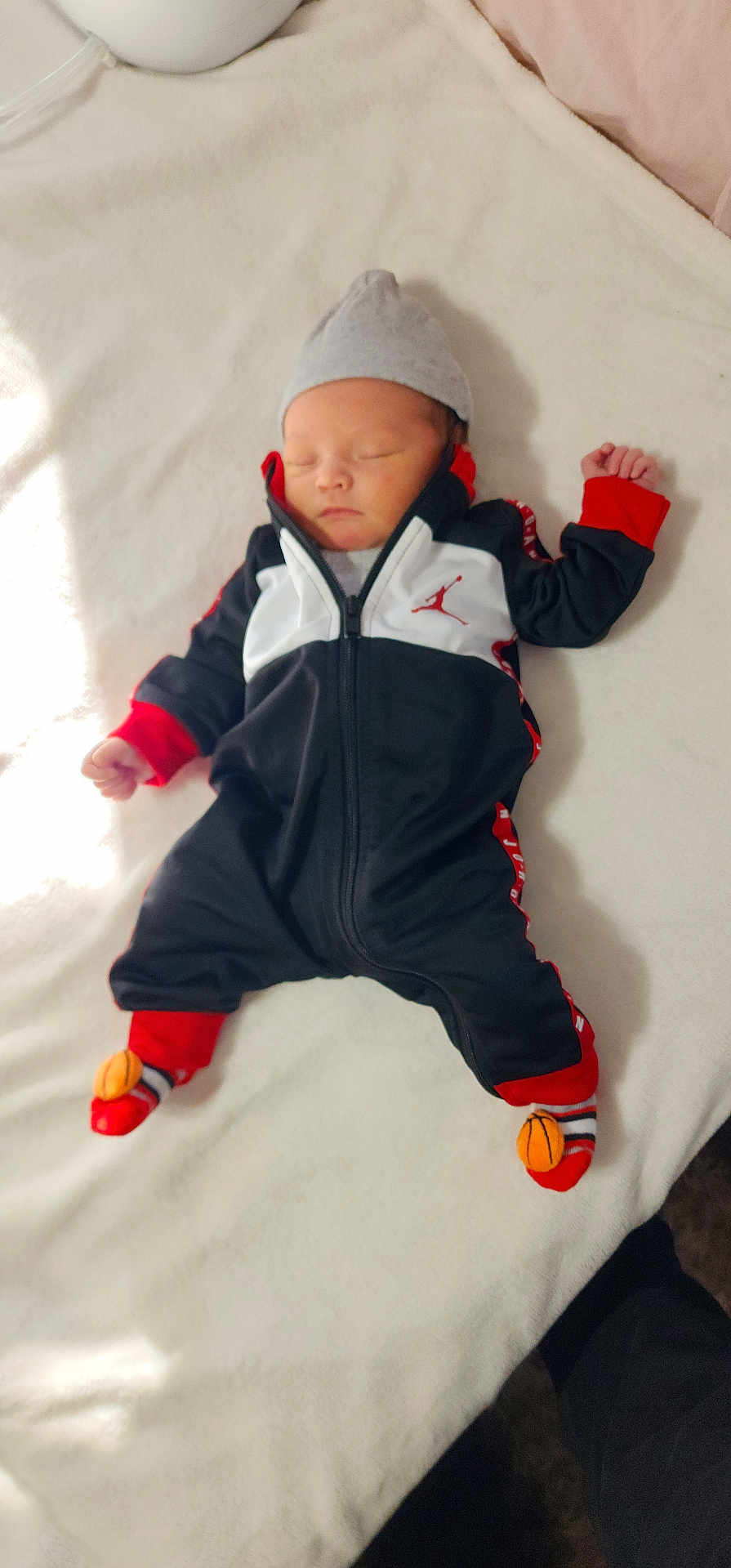 Evander joined the competition — help win amazing prizes! baby, newborn, sleeping, blanket, hat, socks, basketball, clothing, infant, cute, resting, soft, indoors, person, child, cozy, black, white, red, peaceful