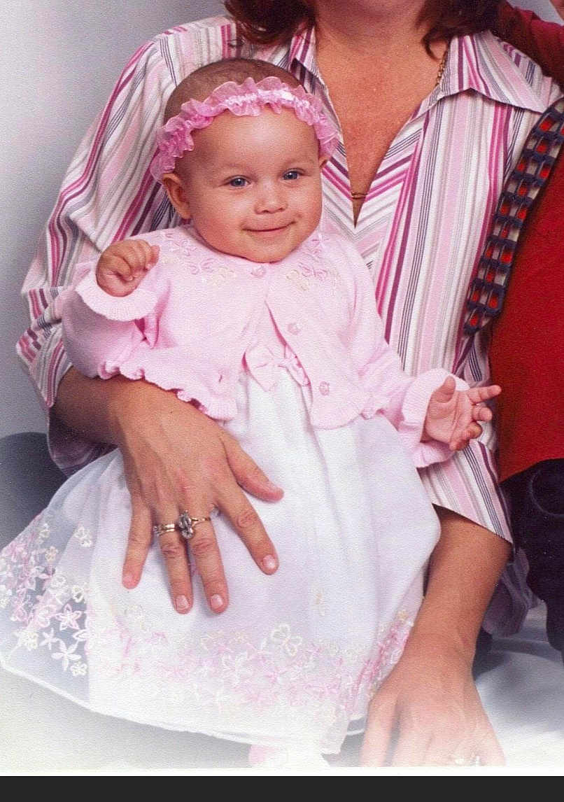 Morgan joined the competition — help win amazing prizes! baby, child, infant, pink_dress, headband, smile, adult_hand, striped_shirt, portrait, indoor, cute, holding, seated, happy, female, person, family, closeup, fashion, accessory