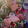 Mazikeen joined the competition — help win amazing prizes! baby, newborn, woman, adult, face, glasses, smiling, holding, cradling, blanket, floral_shirt, patterned_pants, visitor_badge, indoor, chair, quilt, home, portrait, family, parenting