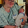 woman, baby, newborn, hospital, gown, glasses, smile, swaddled, infant, mother, indoor, healthcare, patient, bracelet, bedroom, medical, person, holding, portrait, love