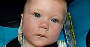 Rodney is registered to the contest to win money with this photo: baby, child, blue_eyes, car_seat, straps, serious_expression, close_up, infant, young_child, clothing, hand, seatbelt, portrait, indoor, cute, face, skin, head, person, sitting