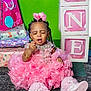 child, baby, birthday, pink_dress, party, presents, gift_bags, blocks, one, shoes, carpet, green_wall, ribbons, braids, beads, celebration, jewelry, happy, indoors, toddler