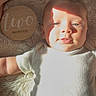 baby, infant, two_months, milestone_sign, wooden_sign, fluffy_rug, sunlight, shadow, white_onesie, cute, portrait, lying_down, newborn, child, soft_texture, skin, face, head, arm, peaceful