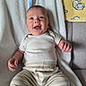 Ozlo joined the competition — help win amazing prizes! baby, infant, smiling, lying_down, blanket, clothing, striped_pants, white_shirt, happy, cute, child, person, indoors, soft_texture, cozy, yellow_blanket, animal_print, toddler, face, expression