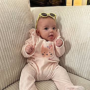 Gabriella participe au concours pour gagner de l'argent avec cette photo : baby, child, couch, cozy, cute, face, footed_pajamas, furniture, headwear, home, indoor, infant, person, pink_clothing, portrait, sitting, smiling, soft_texture, sunglasses, young_child