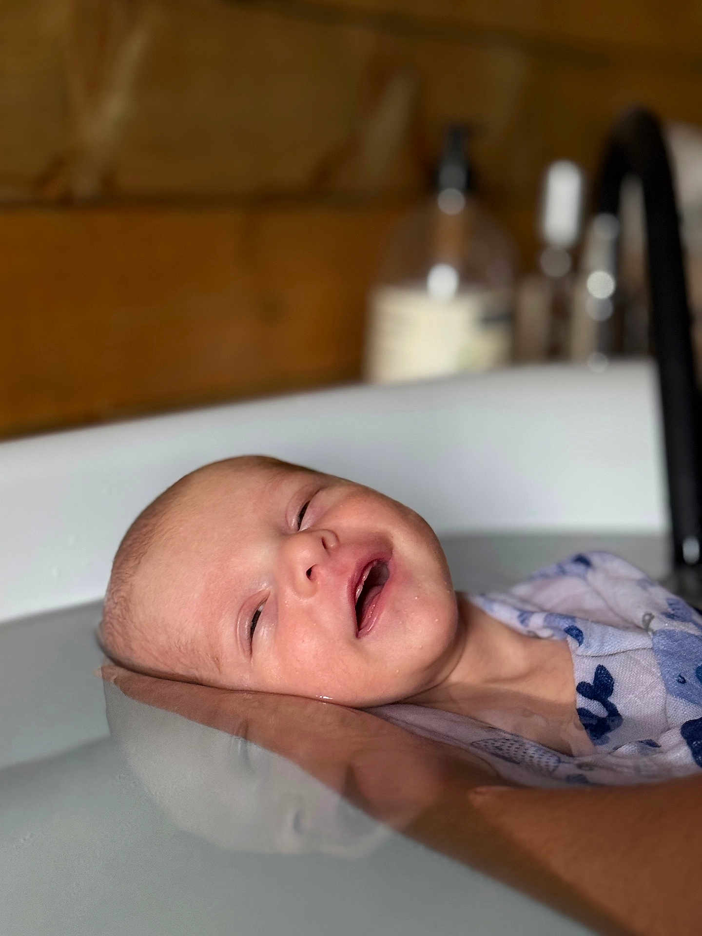 Marceau a rejoint le concours — aidez-le/la à gagner de superbes lots ! baby, bathtub, water, hand, infant, floating, skin, person, relaxation, bath, wooden_background, blurred_background, smiling, closeup, support, child, indoor, cleanliness, hygiene, soft_lighting