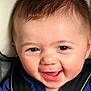 baby, smiling, face, child, car_seat, safety_harness, close_up, happy, infant, skin, hair, eyes, mouth, cute, young, person, clothing, blue_shirt, sitting, portrait