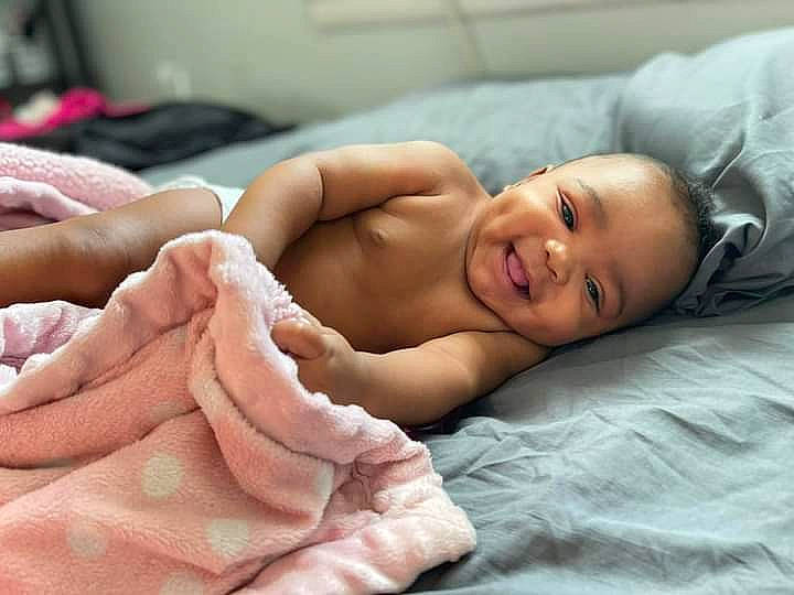 Jakayla joined the competition — help win amazing prizes! abdomen, baby, bedding, child, chin, close_up, comfort, eyebrow, fur, gesture, happy, human_leg, joy, linens, peach, person, room, shoulder, skin, smile