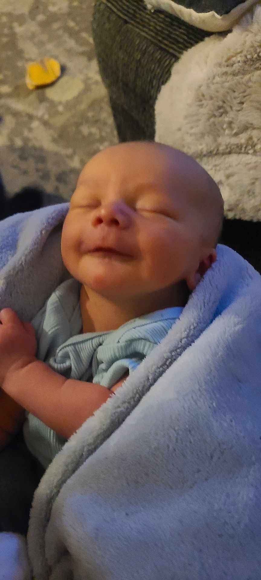 Westyn is registered to the contest to win money with this photo: baby, newborn, infant, sleeping, smiling, blanket, blue_blanket, swaddle, wrapped, face, closed_eyes, arm, hand, soft_texture, couch, sofa, living_room, carpet, portrait, peaceful