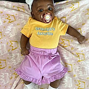 True joined the competition — help win amazing prizes! baby, infant, pacifier, headband, flower, yellow_shirt, purple_shorts, blanket, pink_blanket, crown_pattern, white_socks, ruffled_socks, lying_down, cute, child, clothing, indoor, soft_texture, adorable, portrait