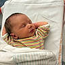 newborn, baby, sleeping, infant, blanket, striped_shirt, hospital_bed, peaceful, child, portrait, cozy, relaxed, indoors, swaddled, cute, head, face, skin, person, young