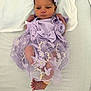 newborn, baby, infant, purple_dress, headband, blanket, lying_down, cute, small_feet, baby_clothing, floral_embroidery, bandage, hospital_band, indoors, portrait, resting, baby_face, soft_light, peaceful, adorable