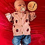 baby, infant, pacifier, sweater, ladybug_pattern, denim_pants, socks, red_blanket, wooden_sign, one_month, cute, newborn, lying_down, portrait, indoors, child, clothing, face, hands, feet