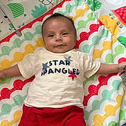 Benjamin is registered to the contest to win money with this photo: baby, infant, child, play_mat, colorful, smiling, shirt, red_shorts, pattern, animal_print, leaf_print, indoor, cute, happy, lying_down, arms_outstretched, face, head, clothing, young_child