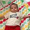 baby, infant, child, play_mat, colorful, smiling, shirt, red_shorts, pattern, animal_print, leaf_print, indoor, cute, happy, lying_down, arms_outstretched, face, head, clothing, young_child