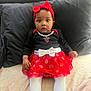 Katelyn is registered to the contest to win money with this photo: baby, child, infant, red_bow, headband, black_top, red_skirt, white_tights, polka_dots, bed, pillow, cute, portrait, sitting, indoors, clothing, person, young_child, expression, curious