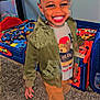 Ezra is registered to the contest to win money with this photo: bed, bedding, carpet, child, dimple, furniture, hair, happy, indoor, jacket, playroom, portrait, shoe, smile, standing, teddy_bear, toddler, toys, tshirt, young_child