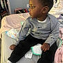 Ezra joined the competition — help win amazing prizes! bed, bedroom, black_pants, blanket, casual_clothing, child, diaper_pack, hair, hands, indoor, looking_right, pillow, portrait, profile_face, side_view, sitting, soft_toy_bedside, sweater, toddler, white_sneakers