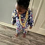 toddler, child, pajamas, gold_chain, indoor, floor, door, standing, clothing, footwear_barefoot, person, cute, young, home, wood_floor, patterned_clothing, jewelry, smiling, hair, portrait