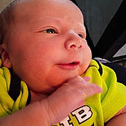 Bryson is registered to the contest to win money with this photo: baby, newborn, infant, face, hand, clothing, yellow_shirt, expression, portrait, closeup, skin, person, cute, young, child, soft_light, indoor, newborn_clothes, baby_face, small_hand