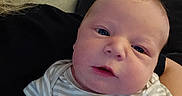 Bryson is registered to the contest to win money with this photo: baby, infant, close_up, face, portrait, striped_shirt, lion_print, hands, couch, pillow, indoor, person, skin, head, eyes, expression, newborn, clothing, relaxing, home