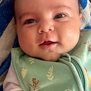 Liam participe au concours pour gagner de l'argent avec cette photo : baby, infant, smiling, face, closeup, green_outfit, animal_pattern, leaf_pattern, blanket, blue, white, eyes_open, cute, child, portrait, soft_lighting, cozy, happy, lying_down, baby_clothing
