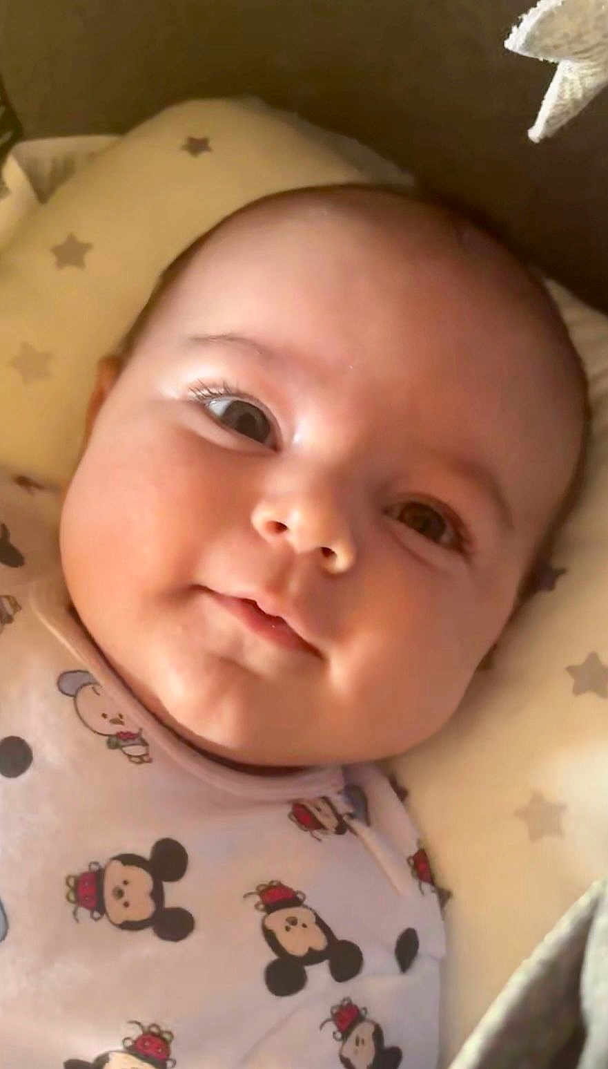 Liam a rejoint le concours — aidez-le/la à gagner de superbes lots ! baby, infant, close_up, face, smile, cute, mickey_mouse, clothing, pillow, stars, child, laying_down, indoors, soft_lighting, young, person, portrait, apparel, sleepwear, adorable