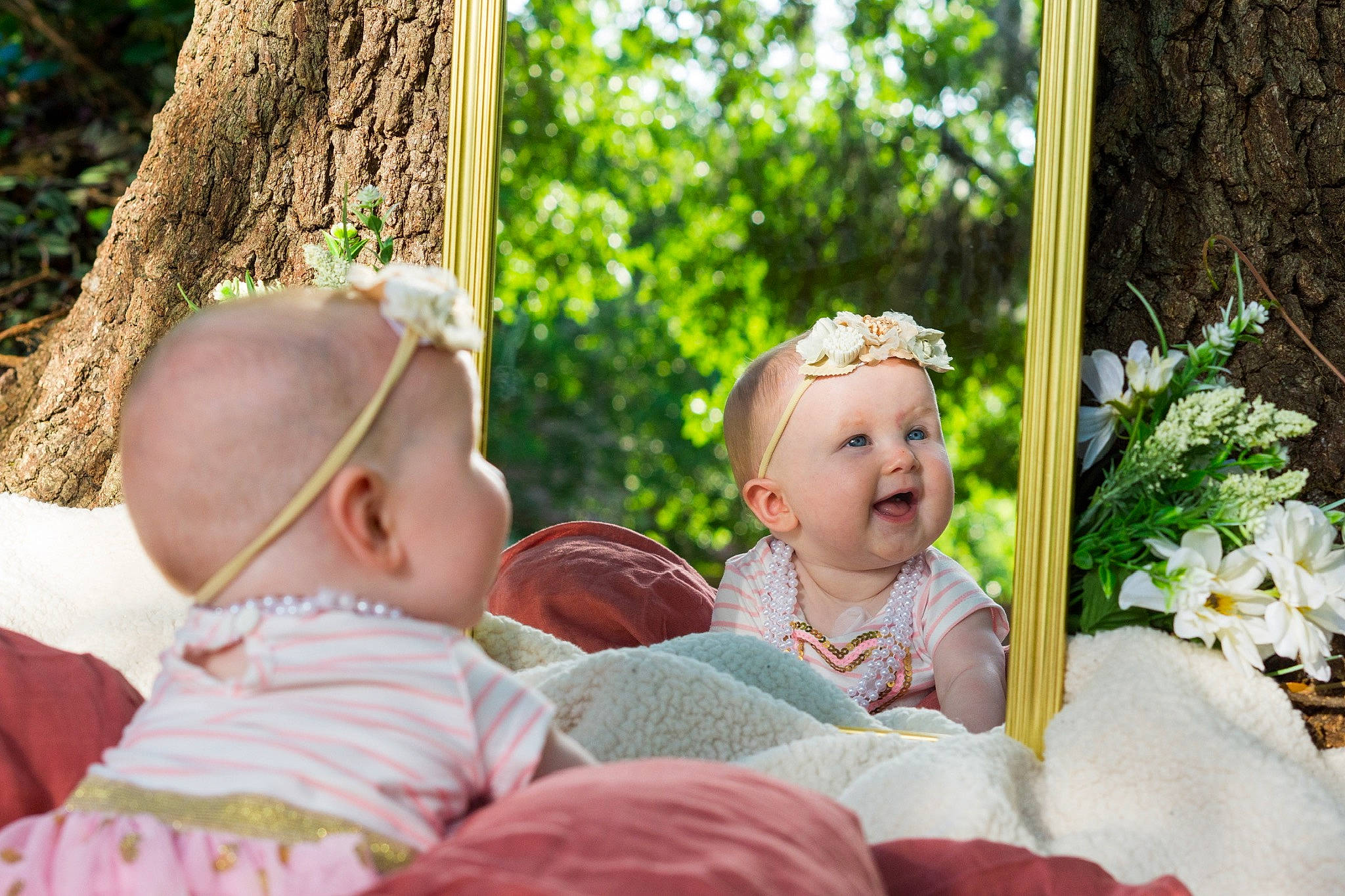 Lilianna is registered to the contest to win money with this photo: baby, baby_toddler_clothing, child, event, eye, facial_expression, flower, fun, grass, happy, head, headgear, leisure, people_in_nature, person, plant, sitting, toddler, tree, trunk