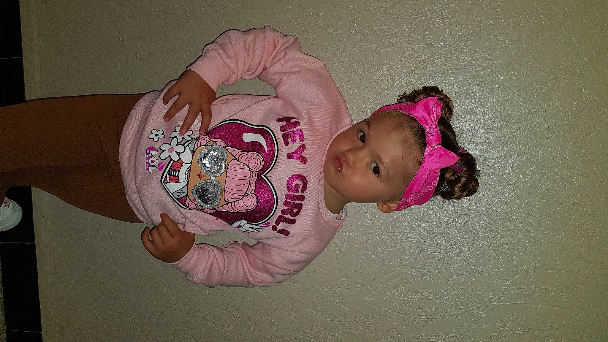 Lina participe au concours pour gagner de l'argent avec cette photo : arm, baby, baby_toddler_clothing, cheek, chest, child, elbow, eye, fashion_accessory, hand, headgear, human_body, mouth, pattern, person, personal_protective_equipment, pink, sleeve, toddler, trunk