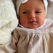 Romy a rejoint le concours — aidez-le/la à gagner de superbes lots ! baby, infant, headband, bow, clothing, soft_toy, stuffed_animal, beige, white, face, portrait, cute, child, newborn, lying_down, cozy, indoors, closeup, skin, expression