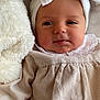 baby, infant, headband, bow, clothing, soft_toy, stuffed_animal, beige, white, face, portrait, cute, child, newborn, lying_down, cozy, indoors, closeup, skin, expression