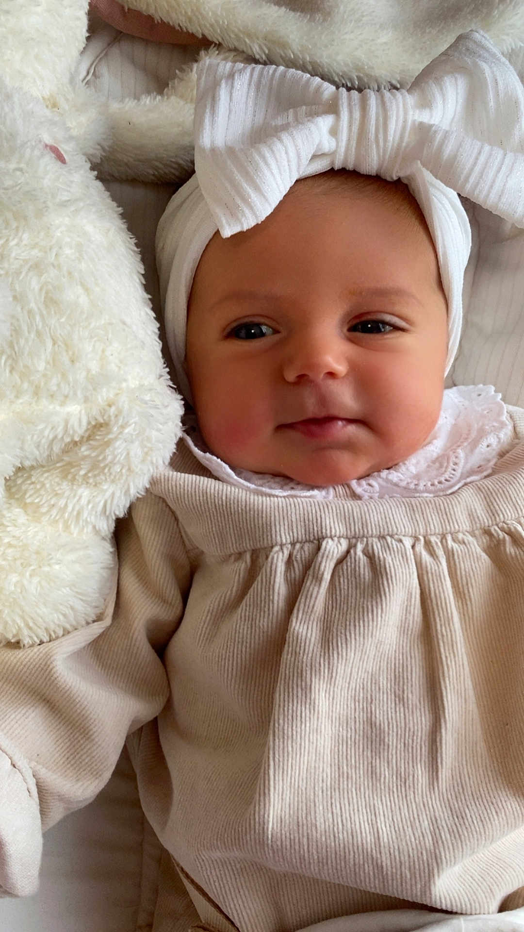 Romy a rejoint le concours — aidez-le/la à gagner de superbes lots ! baby, infant, headband, bow, clothing, soft_toy, stuffed_animal, beige, white, face, portrait, cute, child, newborn, lying_down, cozy, indoors, closeup, skin, expression