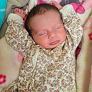 Amber is registered to the contest to win money with this photo: newborn, baby, sleeping, infant, portrait, face, closed_eyes, floral_outfit, onesie, blanket, bedding, cuddled, indoors, resting, peaceful, baby_clothing, pink, patterned, head, photography
