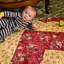 Noah joined the competition — help win amazing prizes! baby, child, striped_pajamas, quilt, floral_pattern, coffee_table, wooden_furniture, carpet, toy_block, indoor, floor, curious, person, home, cozy, infant, laying_down, looking_up, pajamas, room