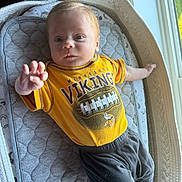 Cullen is registered to the contest to win money with this photo: baby, infant, toddler, yellow_shirt, minnesota_vikings, football_graphic, lying_down, baby_lounger, cushion, gray_padded_mat, window_light, curious_expression, hand_reaching, indoor, soft_light, baby_clothes, red_hair, small_feet, cozy, child